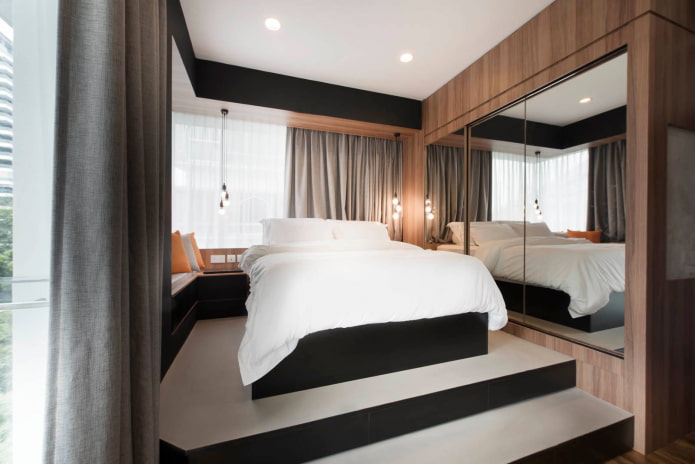 Bed op een verhoogd platform met een spiegel aan de zijkant