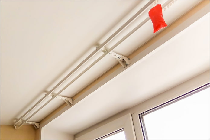 gordijnroede aan de muur onder een spanplafond