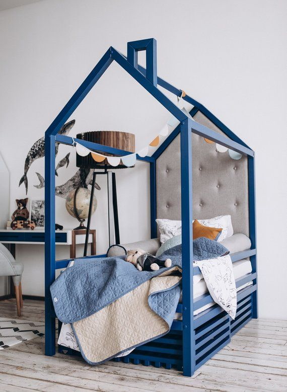 blauw bed in de vorm van een huis in een kinderkamer