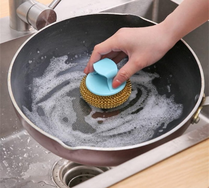 een koekenpan schoonmaken met een harde spons
