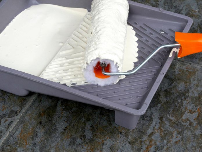 Een roller rollen in een bakje met verf