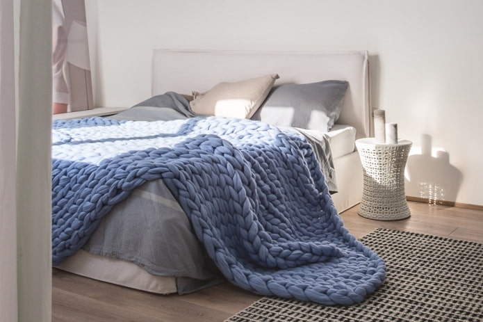 bed met een grote gebreide sprei in de slaapkamer