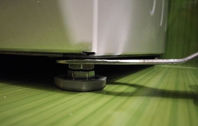 De wasmachine waterpas stellen met de poten