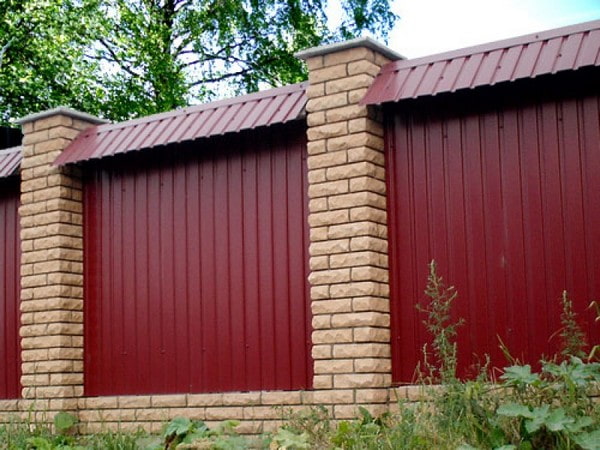 Bordeauxrood hekwerk van gegolfd plaatmetaal met een nok