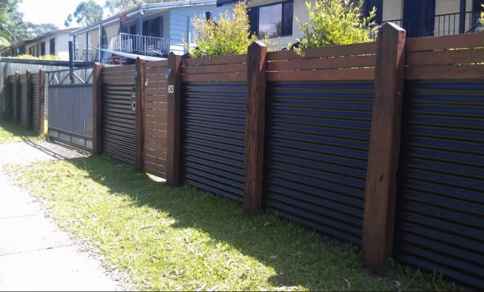 Schutting van golfplaten met houten palen